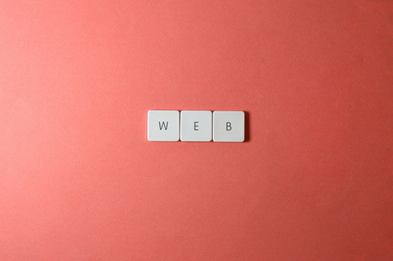 A minimalist photo featuring the word WEB spelled with keyboard keys on a red background.